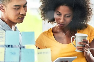 Two coworkers reviewing notes and company stats over morning coffee.