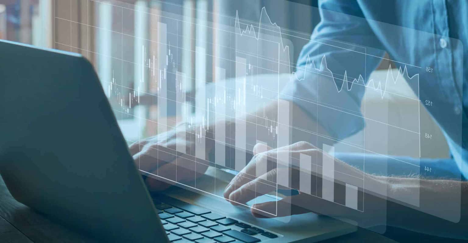A person types on a laptop with transparent digital charts and graphs overlaid, representing data analysis or financial statistics using Instacart Advertising software.