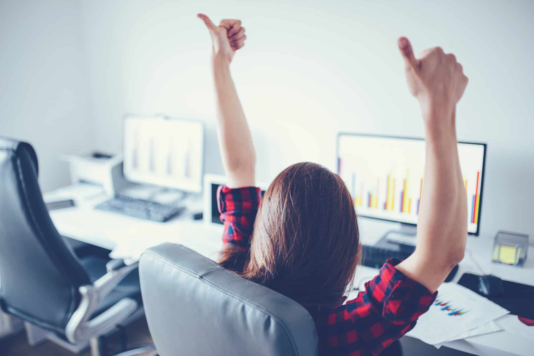 Woman sitting at her desk giving a thumbs up after receiving increasing business development news
