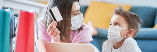 A mom and son looking at each other with masks on debating on an online purchase.