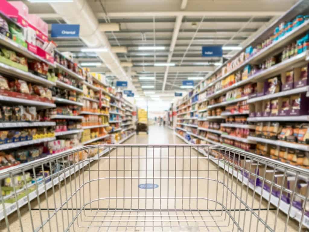 A shopping cart is pushed down the aisle at a grocery store.