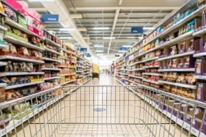 A shopping cart is pushed down the aisle at a grocery store.