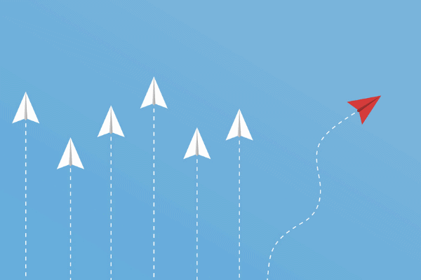 Six white paper airplanes all traveling in a straight line while one red paper airplane deviates to the right by itself.