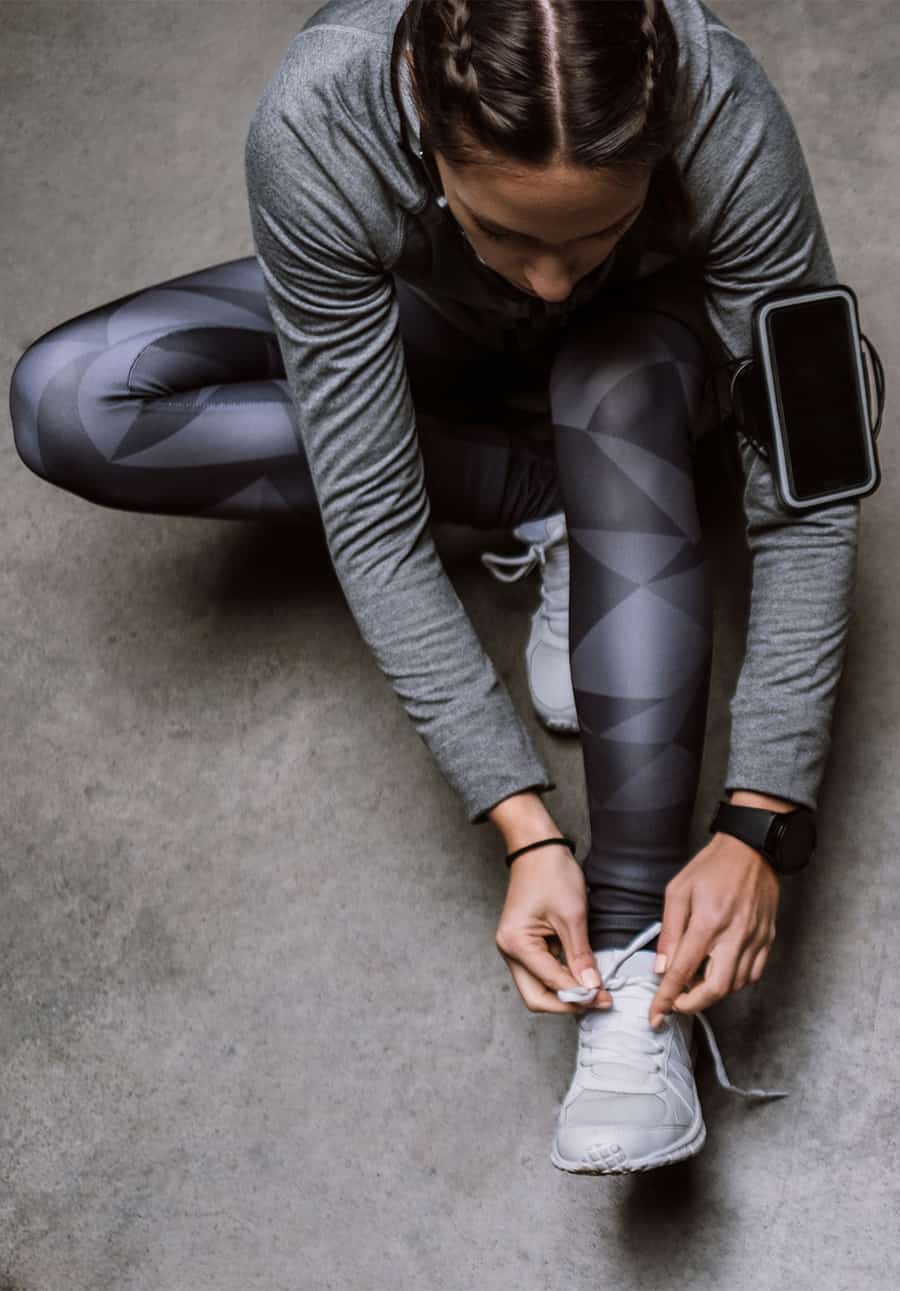 Eine Frau in Sportkleidung bindet sich ihre Turnschuhe, um laufen zu gehen.