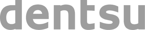 Auf dem Bild ist das Wort „dentsu“ in fetten, kleinen, grauen Buchstaben auf hellem Hintergrund zu sehen.