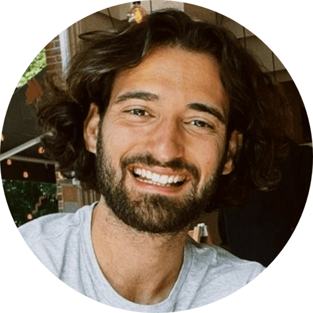 Un homme aux cheveux bruns ondulés mi-longs et portant une barbe sourit. Il porte une chemise gris clair et se trouve à l'intérieur ; il figure dans une étude de cas sur le Retail Media, avec un éclairage chaleureux et des éléments d'arrière-plan flous visibles.