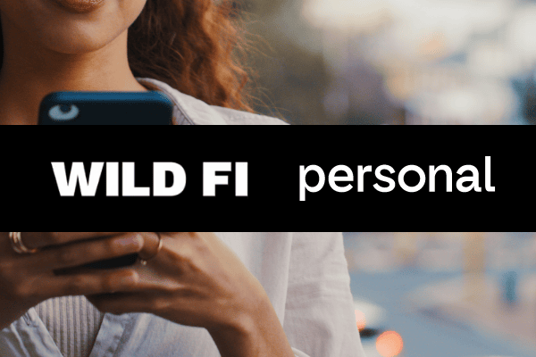 Eine Person, die ein Smartphone in der Hand hält (teilweise zu sehen), auf dessen Display in der Mitte der Text „WILD FI personal“ in fetten weißen Buchstaben steht – das perfekte Bildmaterial für eine Fallstudie zu Paid Search und Paid Social.