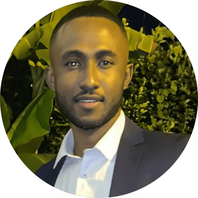 A man wearing a dark blazer and white shirt smiles at the camera. He is standing outdoors at night, with green foliage in the background, possibly after discussing a recent retail media advertising case study.