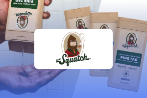 Une personne verse du savon « Dr. Squatch Pine Tar » dans sa main, avec trois flacons de savon Dr. Squatch et le logo Dr. Squatch représentant un homme barbu en arrière-plan — une image idéale pour une étude de cas sur la publicité dans les médias de vente au détail.