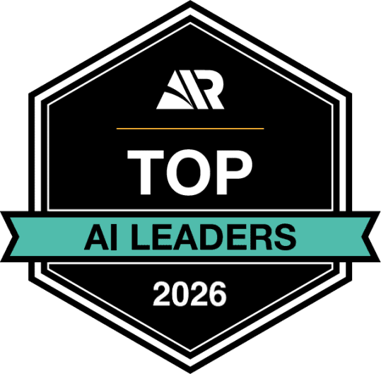 Ein schwarzes, sechseckiges Abzeichen mit den Buchstaben „AR“ oben, der Aufschrift „TOP AI LEADERS“ in der Mitte auf einem blaugrünen Banner und der Jahreszahl „2026“ unten, das eine Auszeichnung oder Anerkennung für Führungsqualitäten im Bereich KI darstellt.