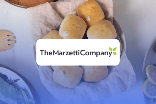 Un panier recouvert d'un tissu contient sept petits pains dorés. Au-dessus du panier, le logo de The Marzetti Company, orné d'une feuille verte, met en valeur une étude de cas sur le Retail Media avec un souci du détail alléchant.