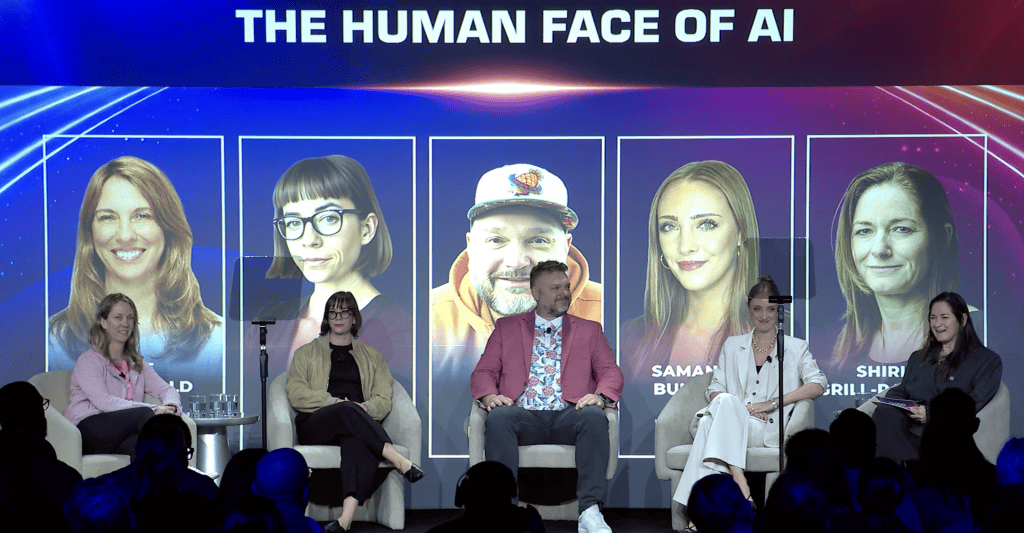 A panel of five people sits on stage under a screen that reads THE HUMAN FACE OF AI, with large photos and names of five individuals displayed behind them. An audience watches in the foreground.