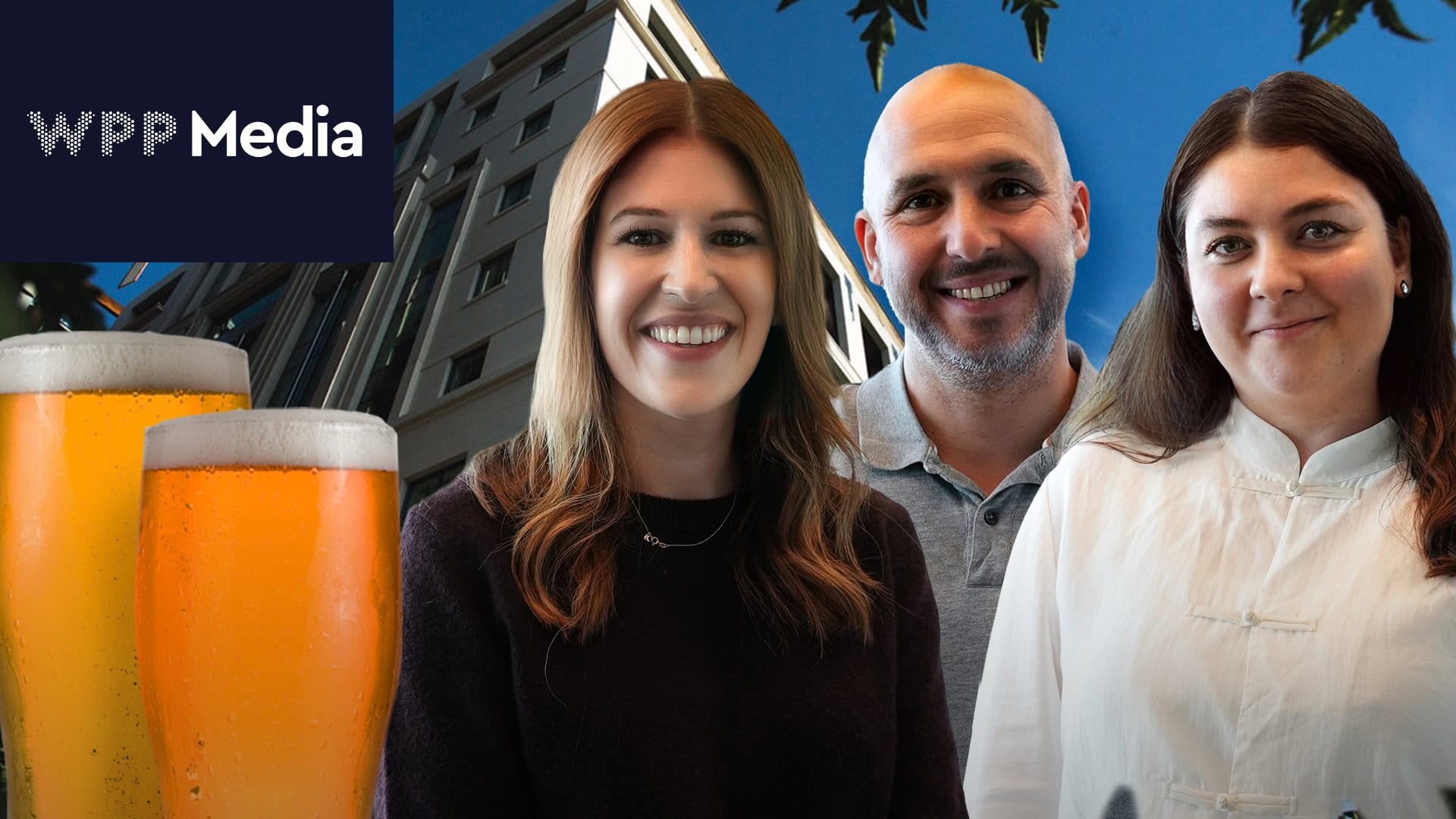Trois personnes souriantes posent devant un bâtiment arborant le logo de WPP Media, avec deux verres de bière au premier plan.